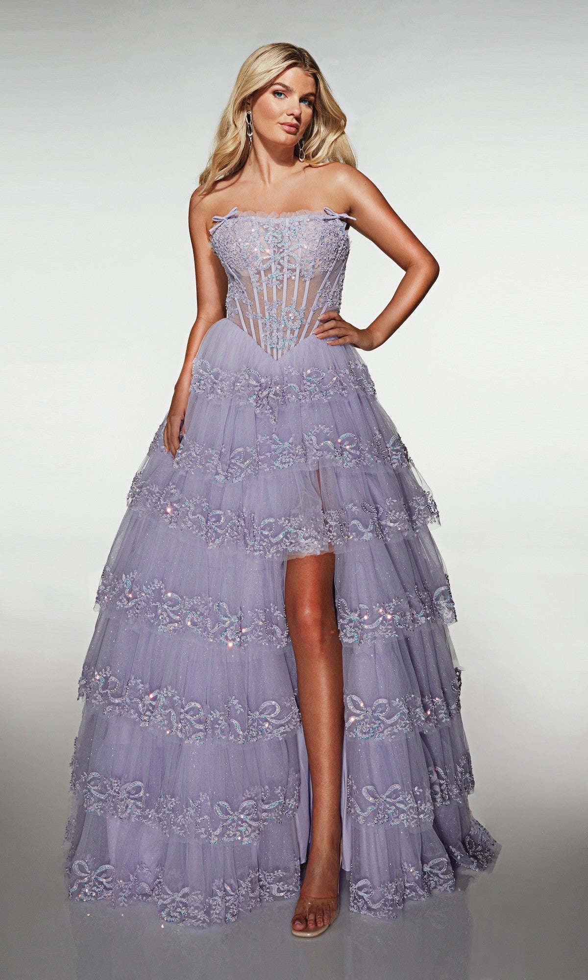 Model wearing the Alyce 62191 long prom dress with a lavender tulle A-line skirt, sheer corset bodice, and floral embellishments, posed against a plain background.
